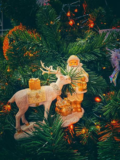 Nestled among the glowing branches of the Christmas tree, a golden Santa figurine stands beside a gentle reindeer carrying a gift. The warm lights reflecting off the ornaments create a magical holiday atmosphere, capturing the charm, warmth, and timeless wonder of Christmas.