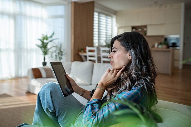 istock Young woman relaxing on couch using digital tablet 2247960390