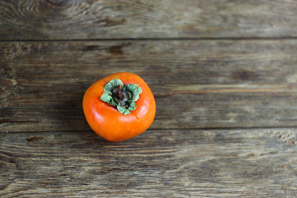 a ripe persimmon lies on a wooden table