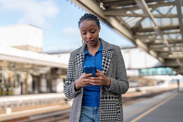 istock Young woman using smartphone at train station platform 2247966943
