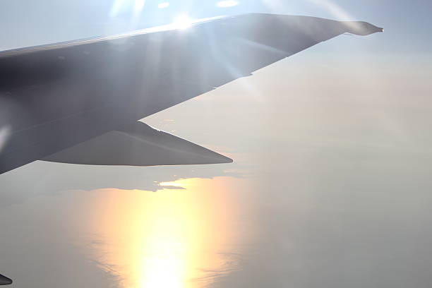 Commercial airplane in flight at cruising altitude with cloudscape below. Aviation travel perspective from passenger seat