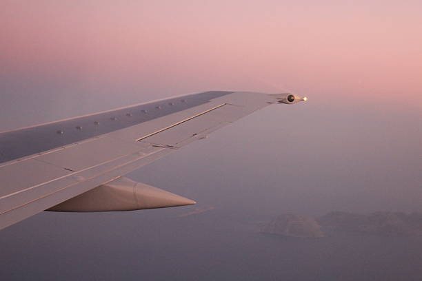Commercial airplane in flight at cruising altitude with cloudscape below. Aviation travel perspective from passenger seat