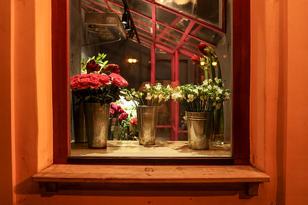 A beautiful display of fresh flowers in metal buckets sits in a window, creating a lovely scene