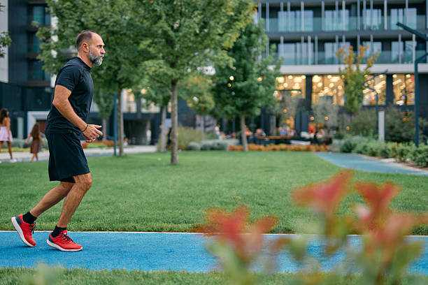 Bearded man running on a blue park track in a modern city, mid-40s focused on fitness and endurance during an outdoor workout for healthy urban lifestyle