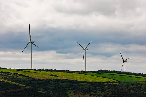 istock Wind turbines stand tall on a green hillside under a cloudy sky 2247988669