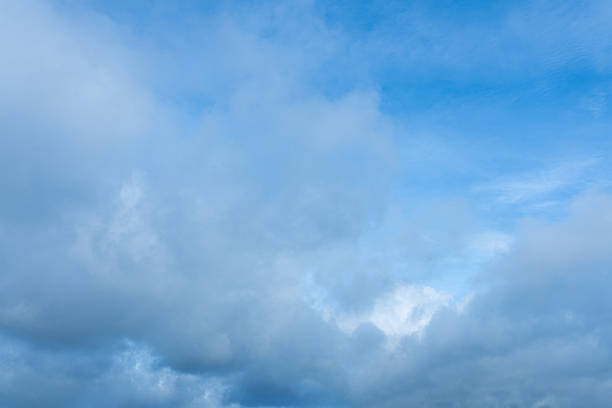 istock Blue sky background partially covered with thick dense gray and white clouds overhead 2247998963