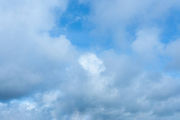 istock Bright blue sky peeking through a dense layer of white and gray cumulus clouds overhead 2247998967