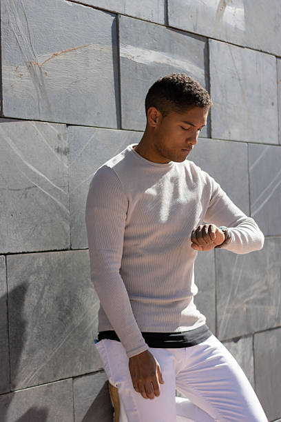 istock Young adult man checking watch waiting in urban setting 2248000196