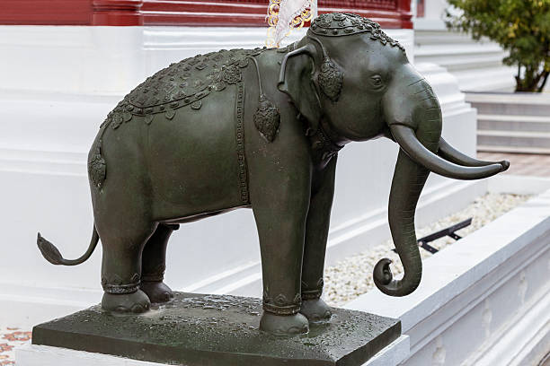 A detailed bronze elephant statue with elaborate decorations stands gracefully outside a temple in Chiang Mai, Thailand. Its majestic presence embodies traditional Thai artistry and cultural heritage.