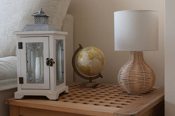 istock Cozy home decor featuring a white lantern with a candle, a vintage world globe, and a stylish rattan base lamp on a textured wooden side table, creating a warm, inviting atmosphere 2248022199