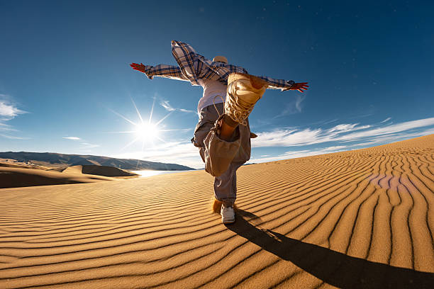 Happy young woman girl tourist is having fun and runs at desert sunset against blue sky and sand dune