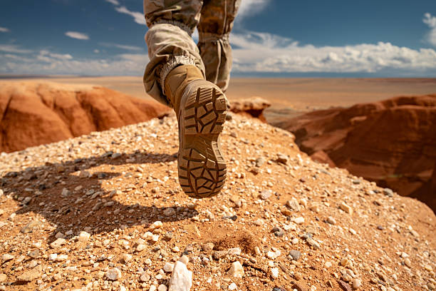 Close up photo of hikers leg while he is going at desert hill