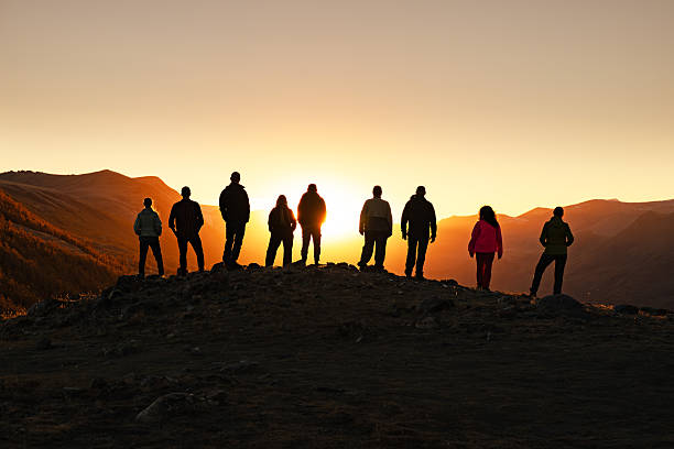 istock Large group of people silhouettes at sunset mountain 2248026828