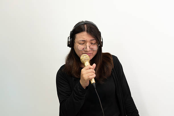 Beautiful asian woman (LGBTQ) is a singer. She enjoying sing a song or karaoke in music studio with microphone condenser and headphones for fun or voice creative