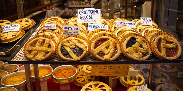 Bologna - Italy - November 23, 2025: A tempting array of traditional italian crostatine pastries showcasing various fruit jams and chocolate fillings in a bakery display at christmastime.
