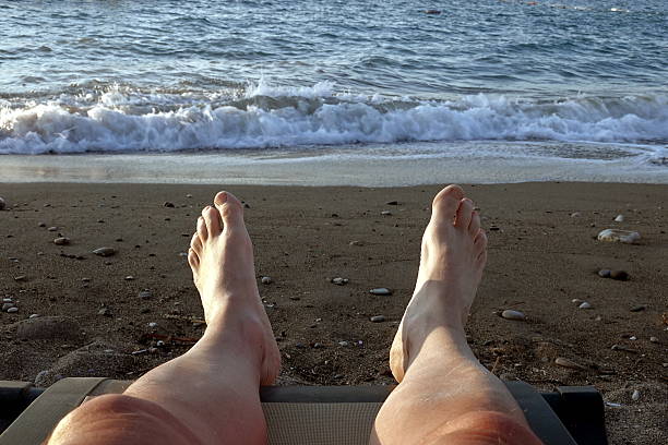 istock Tired legs of a man on the seashore. 2248031449