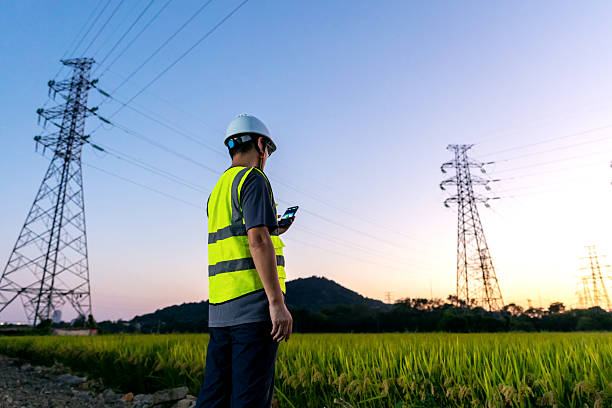 istock An Asian engineer uses his mobile phone under a power line tower. 2248031695