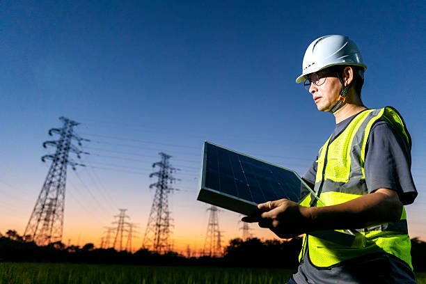 istock At sunset, an Asian engineer stands beneath a power line tower, holding a solar panel. 2248032031