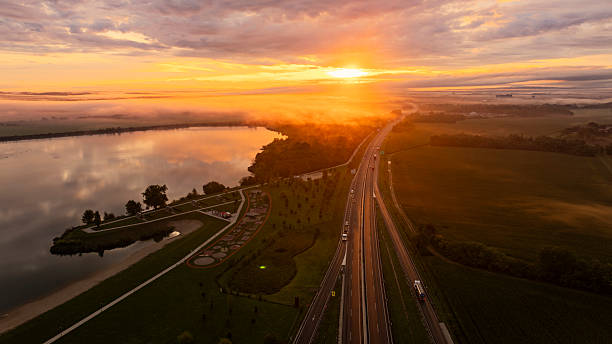 istock Morning Light Cascading Over Highway and Tranquil Waterway 2248034927