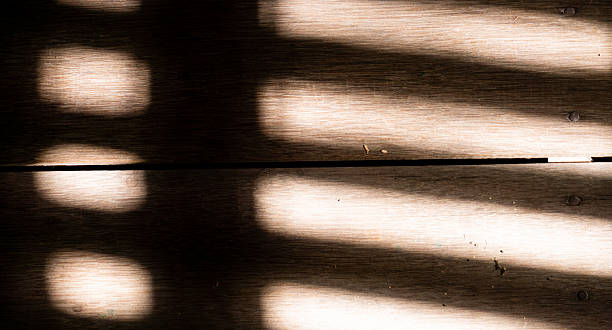 istock Soft sunlight cast abstract patterns across weathered wooden planks, creating a warm contrast of highlights and shadows. Minimalist natural texture ideal for backgrounds and design 2248039354