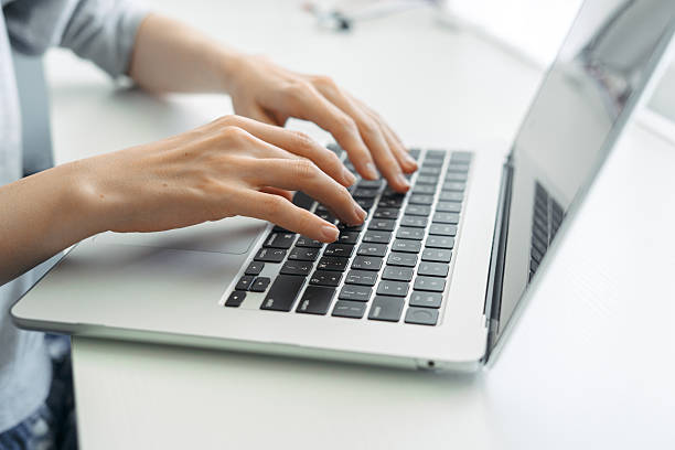 istock Close-up of hands typing on laptop keyboard in bright office 2248039394