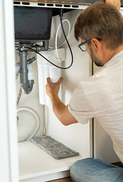 istock Plumber installs water filter under kitchen sink. Replacement water purifier 2248040816