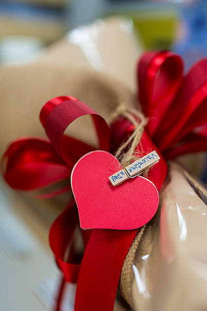 Red bow on the bouquet and paper red heart. Close up