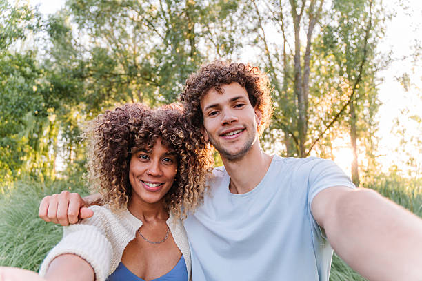 istock Happy young couple taking a selfie outdoors, smiling and connecting, enjoying shared time in nature with bright sunlight filtering through trees 2248042879