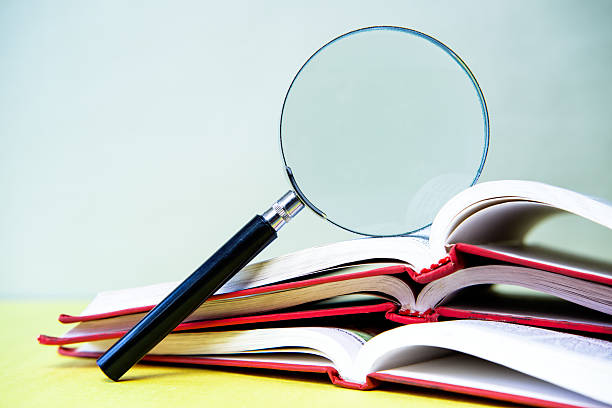 istock Magnifying glass and books on yellow background. 2248045844