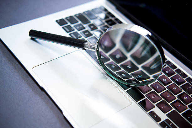 istock Laptop and magnifying glass on black background. 2248045895