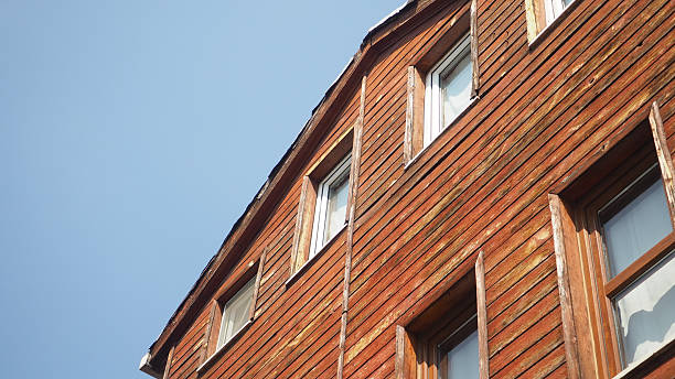A close-up view of a wooden house's upper facade against a bright sky.