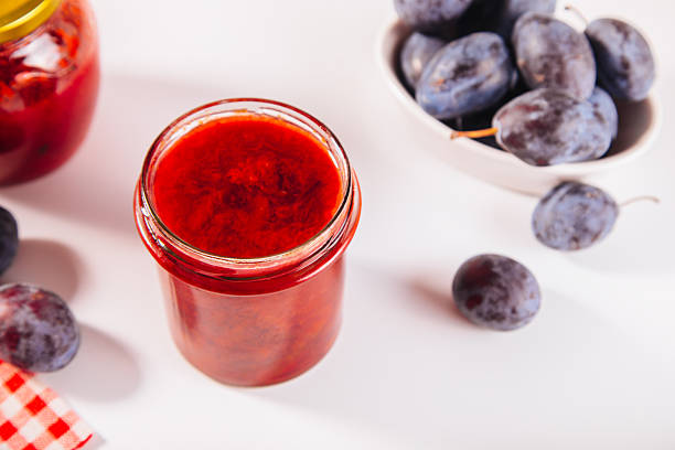 Ripe plums and glass jar of plum jam, preserving for the winter
