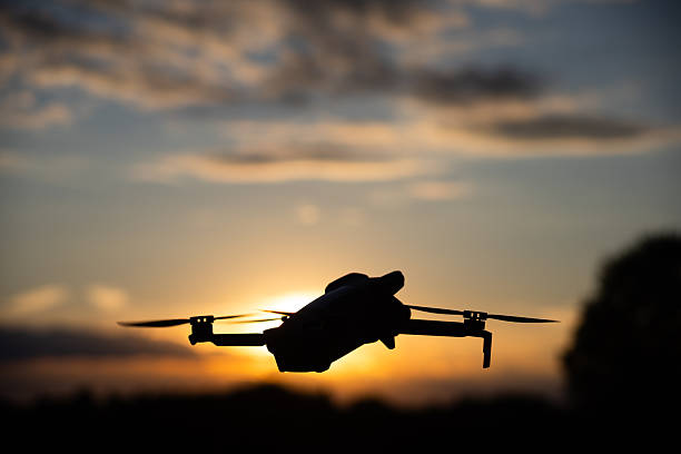 Hamburg, Germany - September 30, 2025: Silhouette of a Drone Flying in the Sky at Sunset with Glowing Sunlight and Scenic Cloudscape in the Background