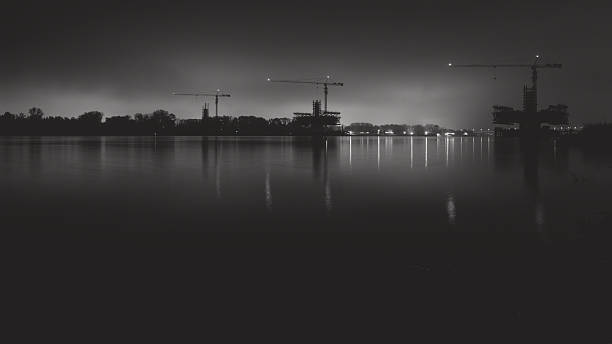 Cranes and structural structures on the river in a foggy night. Monochrome photography