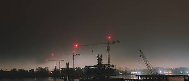 Cranes and structural structures on the river in a foggy night.