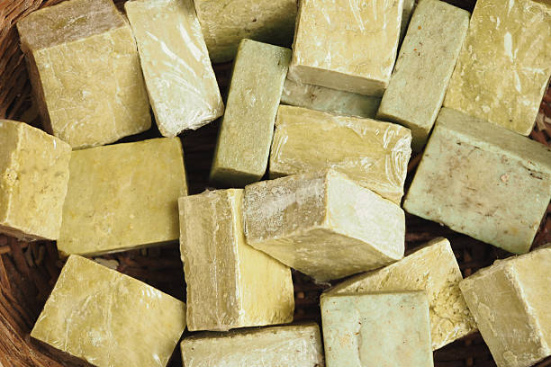 Various handmade soap bars in green and yellow tones are arranged in a basket.