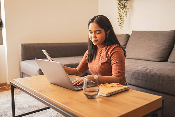 istock Woman working on laptop and using phone in a cozy home environment 2248056081