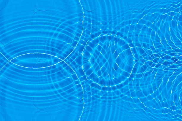 Blue water with ripples on the surface. Defocus blurred transparent blue colored clear calm water surface texture with splashes and bubbles. Water waves with shining pattern texture background.