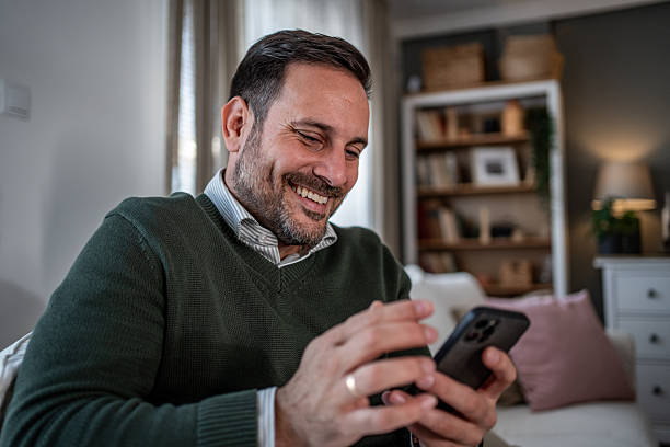 istock Mature adult man smiling using phone at home 2248058516