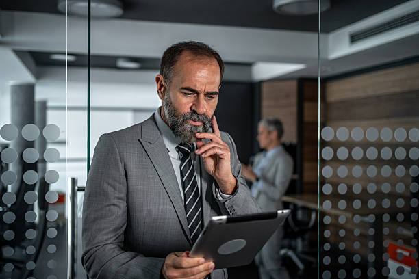 istock Mature businessman concentrating while working on digital tablet 2248059646