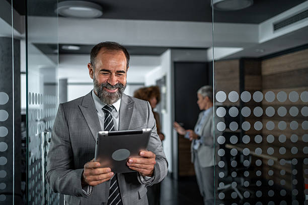 istock Happy mature businessman using digital tablet walking in office 2248059656