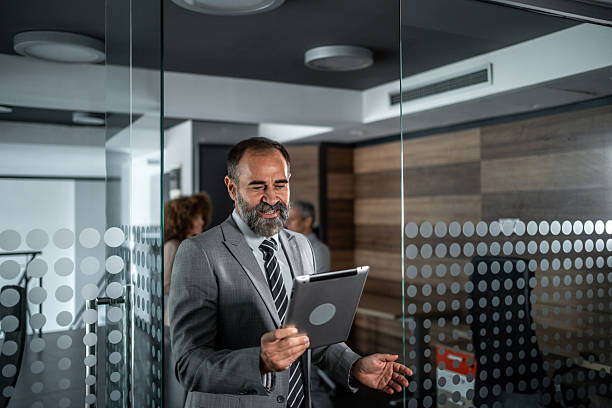 istock Mature businessman checking tablet in modern office hallway 2248059668
