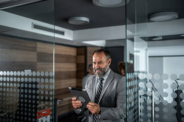 istock Mature businessman checking digital tablet in modern office 2248059678