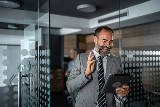 istock Mature businessman waving during video call on tablet 2248059705
