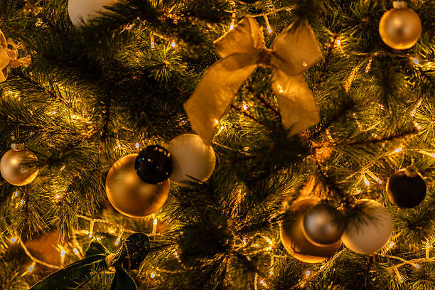 A Christmas tree decorated with festive bows, golden ornaments, and warm fairy lights creating a rich seasonal atmosphere.