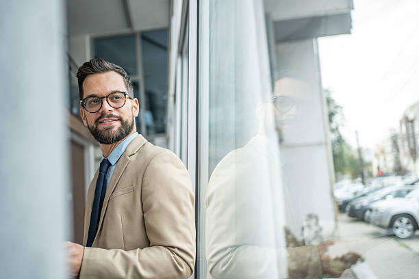 istock Young professional businessman standing by modern building reflection 2248072519