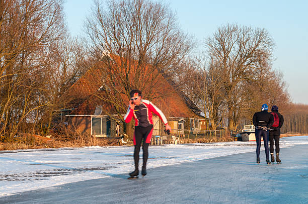 Tytsjerksteradiel, Netherlands - February 10, 2012. Winter scene showing people ice skating on a forzen canal in northern friesland.