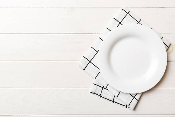 istock Top view on colored background empty round white plate on tablecloth for food. Empty dish on napkin with space for your design 2248073823