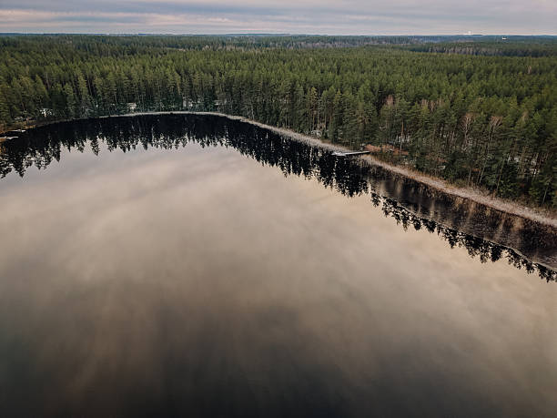 istock Serene landscape featuring a tranquil lake reflecting surrounding evergreen trees under a cloudy sky, creating a peaceful atmosphere in nature's embrace 2248074321