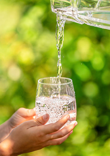 istock Fresh drinking water pouring into glass outdoors with human hands holding the cup 2248077092
